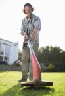 Skillful caucasian man using weed whacker in backyard — Stock Photo