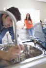 Frau beobachtet Klempnerarbeiten an Küchenspüle — Stockfoto