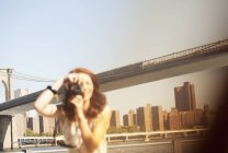Mujer tomando fotos por puente urbano - foto de stock