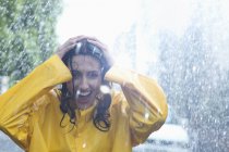 Счастливая женщина с руками на голове под дождем — стоковое фото