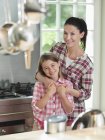Жінка обіймає дочку на кухні — стокове фото