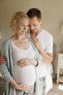 Sorridente uomo abbracciare donna incinta — Foto stock