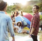 Men carrying cooler outside tents at music festival — Stock Photo