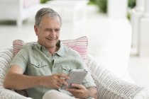 Older man using tablet computer on porch — Stock Photo