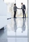 Businessmen shaking hands at modern office — Stock Photo