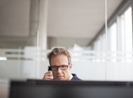 Бізнесмен розмовляє по телефону за столом в сучасному офісі — стокове фото
