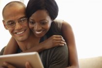 Giovane attraente coppia utilizzando tablet computer sul divano — Foto stock