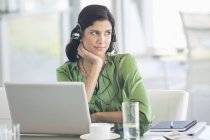 Geschäftsfrau trägt Kopfhörer am Schreibtisch im modernen Büro — Stockfoto