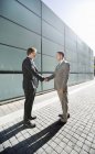 Businessmen shaking hands on city street — Stock Photo