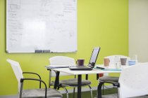 Ноутбук и кофейные чашки на столе для переговоров в современном офисе — стоковое фото