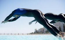 Уверенный и сильный триатлонисты ныряя в бассейн, вид сбоку — стоковое фото