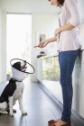 Женщина дает собаке в конусе удовольствие на кухне — стоковое фото