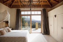 Кровать с балдахином и французские двери, ведущие на балкон в спальне — стоковое фото