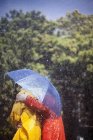 Пара обнимающихся под зонтиком под дождем — стоковое фото