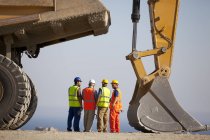 Workers talking by machinery in quarry — Stock Photo