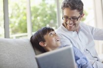 Padre e figlio utilizzando tablet sul divano — Foto stock