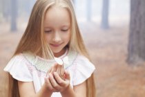 Close up of girl holding butterfly in woods — Stock Photo