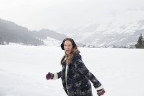 Porträt einer begeisterten Frau, die im verschneiten Feld läuft — Stockfoto