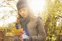 Girl carrying autumn leaf outdoors — Stock Photo