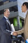 Two businessmen shaking hands outdoors — Stock Photo