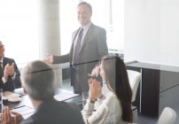 Empresários aplaudindo colega em reunião no escritório moderno — Fotografia de Stock