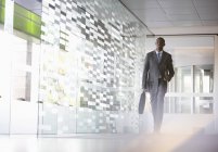 Homme d'affaires avec mallette marchant dans le hall au bureau moderne — Photo de stock