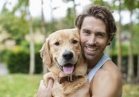 Homme souriant caressant chien à l'extérieur — Photo de stock