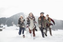 Счастливые друзья, играющие на снежном поле — стоковое фото
