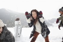 Amigos entusiastas disfrutando de la pelea de bolas de nieve en el campo - foto de stock