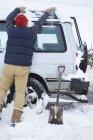 Вид сзади на человека, выкапывающего машину из снега — стоковое фото
