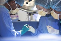 Cirurgiões dobrados sobre o paciente na mesa de operação — Fotografia de Stock