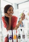 Mujer examinando el producto para el cuidado de la piel en la farmacia - foto de stock