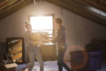 Young couple unpacking box in attic — Stock Photo