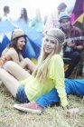 Porträt einer Frau, die mit Freunden vor Zelten auf einem Musikfestival abhängt — Stockfoto