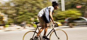 Вид сбоку человека, катающегося на велосипеде по городской улице — стоковое фото