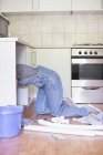 Умелая женщина работает под кухонной раковиной — стоковое фото