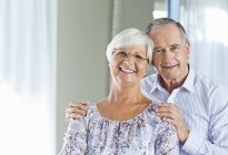 Älteres Paar lächelt gemeinsam drinnen — Stockfoto