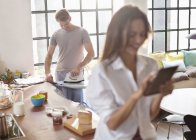 Frau bügelt mit digitalem Tablet in Küche — Stockfoto