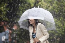 Happy woman hiding under umbrella in rain — Stock Photo