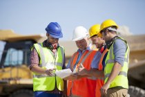 Workers and businessman talking in quarry — Stock Photo
