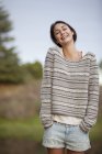 Portrait of smiling woman with hands in short pockets — Stock Photo
