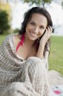 Ritratto ravvicinato di donna sorridente avvolta in una coperta — Foto stock