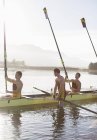 Rowing team lifting oars in lake — Stock Photo