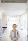 Doctor looking up at sign in hospital corridor — Stock Photo