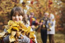Menina brincando com folhas de outono no parque — Fotografia de Stock