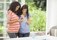 Pregnant woman showing friend sonogram — Stock Photo