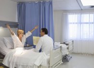 Лікар розмовляє з веселим пацієнтом у лікарняній кімнаті — стокове фото