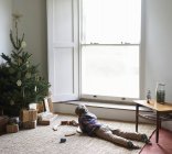 Garçon jouer avec train par arbre de Noël — Photo de stock