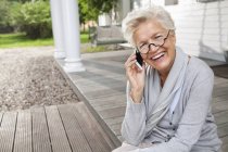 Donna che parla al cellulare sul portico — Foto stock