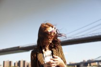Femme en nouveauté lunettes de soleil par paysage urbain — Photo de stock